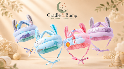 Three padded baby headrests with bunny ears are displayed against a warm beige background with decorative leaves and soft props. The headrests come in pastel blue, pink, and lavender, with printed patterns including stars, a rocket ship, and a zebra.